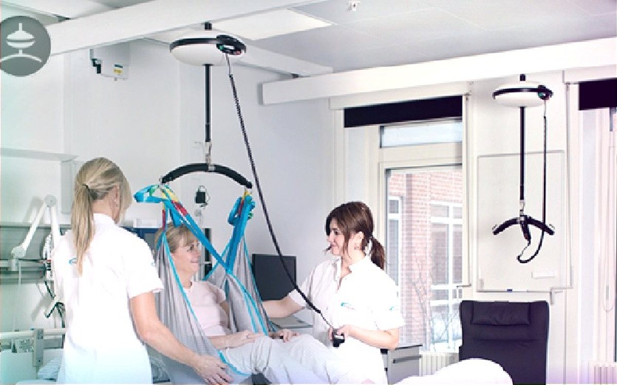 Carers using a ceiling hoist and sling to transfer a client